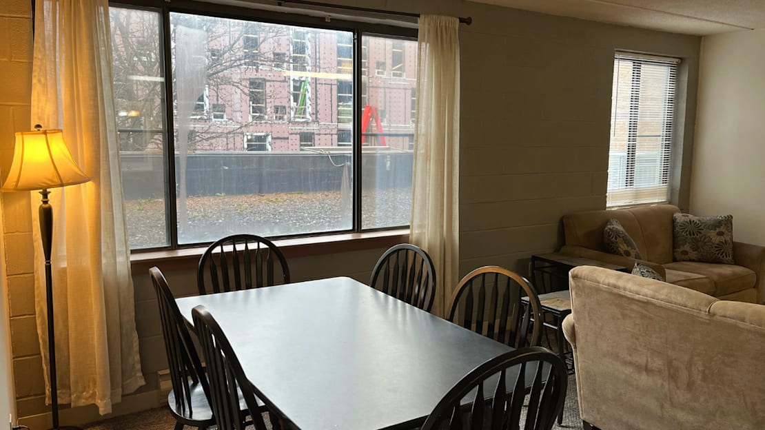 A dining room with a table, chairs, and a lamp.
